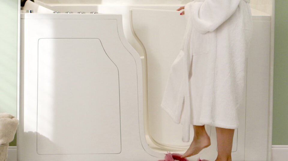 Person entering walk-in bathtub in robe.