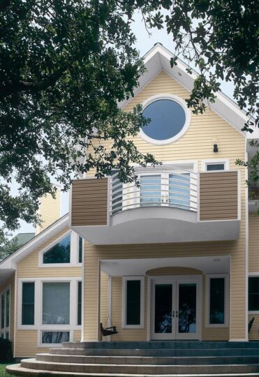 Yellow house with round window and balcony.