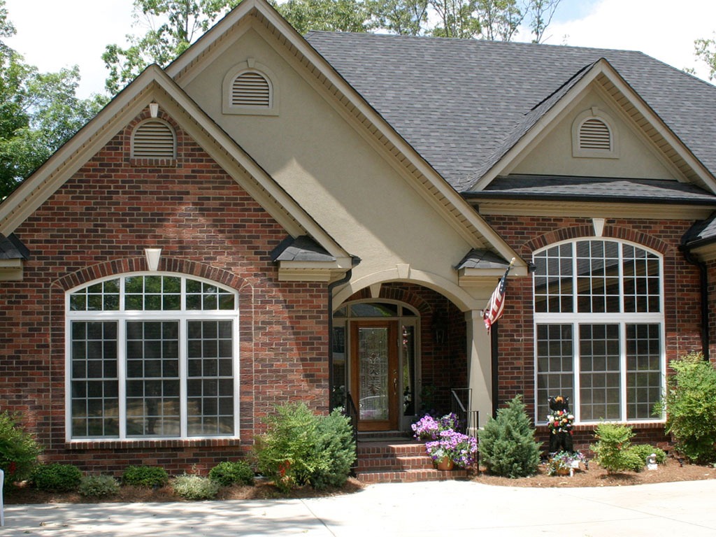 Brick house with large windows and American flag.