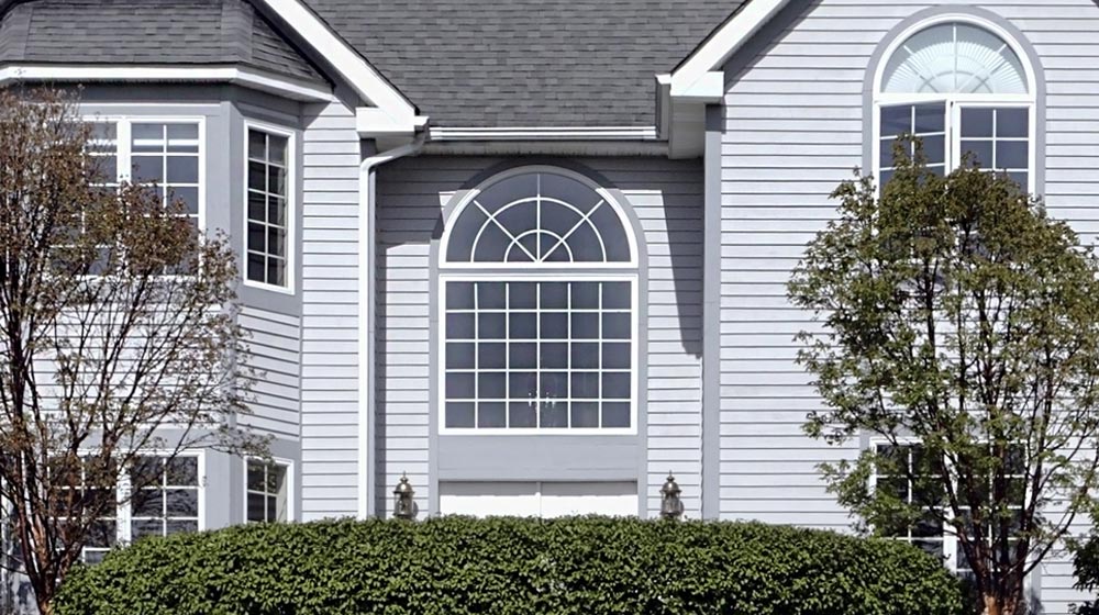 Modern blue house with large windows at dusk.