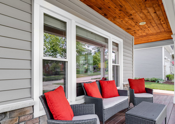 Modern porch with gray wicker furniture and red pillows.